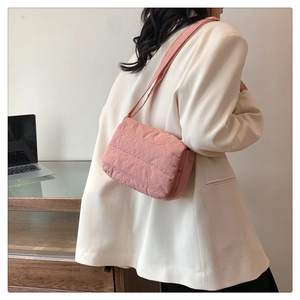 Close-up of pink quilted crossbody bag with wide strap on model in office setting