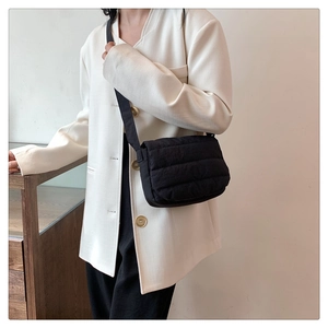 Quilted black puffer crossbody bag worn with white blazer showing everyday styling