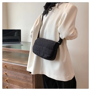Lifestyle shot of a black quilted crossbody bag worn by a model in a minimalist office