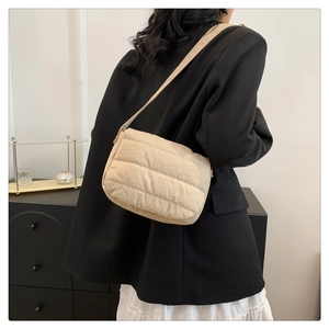 Detailed back view of a beige quilted crossbody bag styled on a model in a black blazer