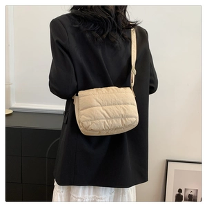 Detail of light beige quilted crossbody bag with soft padded texture and slim strap