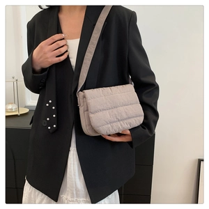 Detail of taupe quilted crossbody bag showing soft nylon material and shoulder strap