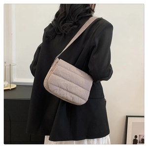 Quilted crossbody bag in light brown worn by a model in a minimalist home setting