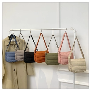 Multiple colors of quilted nylon crossbody bags hanging on a display rack for selection