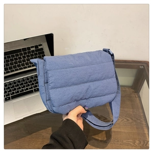 Detail shot of the blue quilted puffer crossbody bag with soft padded texture and strap