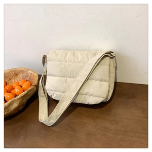 Detailed close-up of a beige quilted puffer shoulder bag on a rustic wooden table
