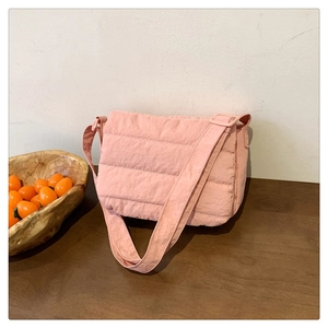 Detailed close-up of pink quilted puffer shoulder bag with soft nylon texture and strap