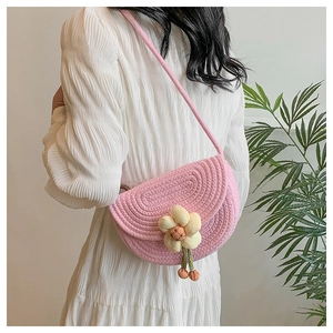 Close-up of pink woven saddle bag with a handmade floral accent and subtle textures