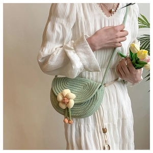 Close-up of green crochet crossbody bag with yellow knit flower and wooden bead tassel