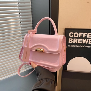 Pink leather crossbody handbag with gold hardware and fashion tag in a lifestyle setting