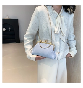 Détail du sac nuage plissé bleu clair avec poignée dorée et bandoulière sur le mannequin