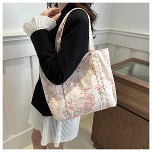 Detail of floral canvas tote bag with pink flower patterns worn by a model