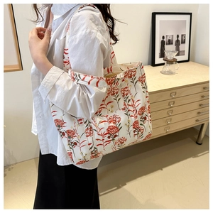 Detail of canvas tote bag with red floral print and reinforced stitching on straps