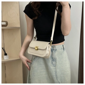 Crossbody square bag in cream faux leather with gold buckle shown on a model