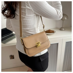 Detail view of camel crossbody bag with gold buckle clasp and adjustable leather strap