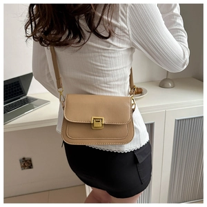 Detail of light brown leather crossbody bag with gold metal buckle on female model