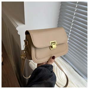 Detailed close-up of a beige crossbody bag with a golden square metal push-lock closure