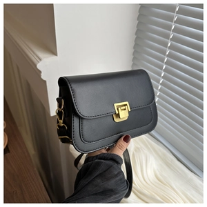 Close-up of a black leather crossbody bag featuring a distinctive gold metal lock closure
