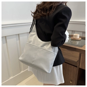 Détail du sac cabas gris clair avec poche avant montré porté à l'épaule pour le style