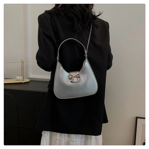 Detail of silver hobo bag with metallic bow charm and chain strap on a model