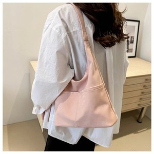 Vue détaillée d'un grand sac cabas rose pâle porté par un mannequin dans un style décontracté
