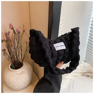 Close-up of black bubble textured fabric handbag with LOVE FASHION woven label detail