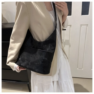 Gros plan du grand sac cabas noir texturé avec poche avant porté à l'épaule