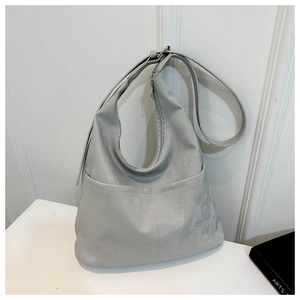 Détail du sac hobo gris clair montrant le cuir synthétique mat et la boucle de la bandoulière