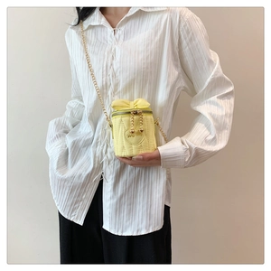 Detailansicht der hellgelben Mini-Eimertasche mit Steppmuster und goldener Kette