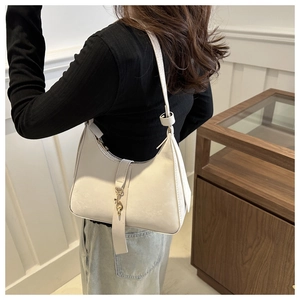 Chic cream leather shoulder bag with gold hardware shown on model in minimalist setting