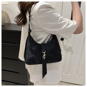 Detail view of black crescent underarm bag with golden metallic hook and matte leather texture