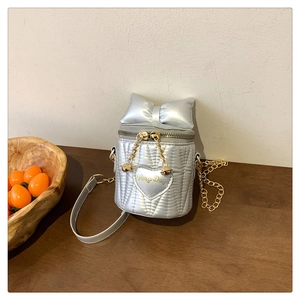 Detail der silbernen Beuteltasche mit Schleife und Herz-Stickerei an goldener Kette