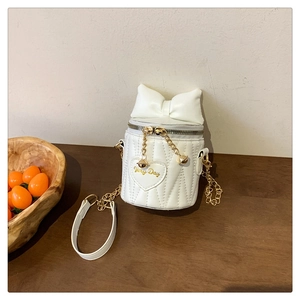 Detail der weißen Stepp-Eimertasche mit großer Schleife und goldener Very Day Herz-Stickerei