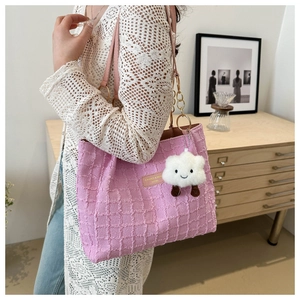 Detail of pink waffle texture tote bag with plush charm and leather straps in a home setting