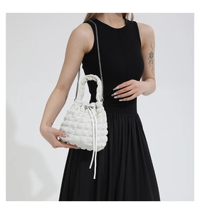 Close-up of white popcorn texture bucket bag with silver chain worn by a model