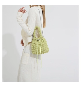 Detail showing light green popcorn textured drawstring bucket bag with silver chain strap