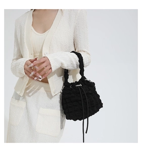 Detail of black puff bucket bag showing textured bubble fabric and silver chain strap