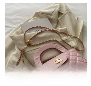 Detail of pink quilted leather bag with adjustable gold ball chain and twist lock