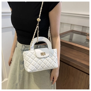 Détail du sac à main matelassé blanc avec fermoir doré et bandoulière en chaîne