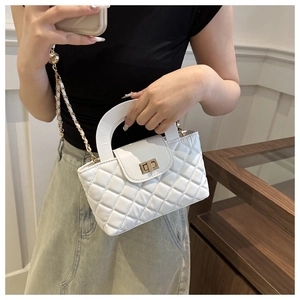 Detail of white quilted crossbody bag with golden twist lock and chain strap