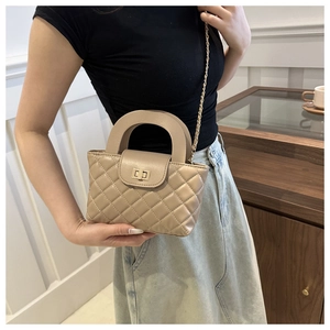 Gros plan d'un sac bandoulière beige matelassé avec chaîne dorée porté par un mannequin