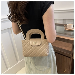 Detail of beige quilted shoulder bag with gold metal twist lock and elegant chain strap
