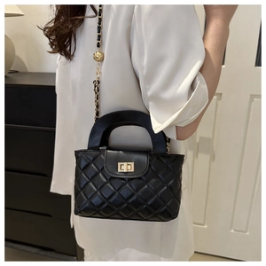 Detail of black quilted leather handbag featuring a gold twist lock and chain strap