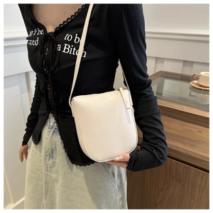 Close-up of white lychee pattern saddle bag with zipper and slim shoulder strap detail