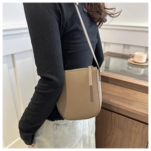Lifestyle shot of a brown lychee pattern saddle bag styled with casual denim and top