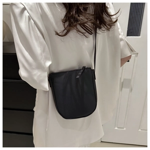 Detail of minimalist black crossbody bucket bag with litchi grain leather and U-shaped design