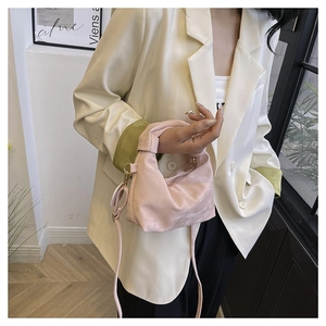 Detail of light pink handbag with a unique knot handle design and detachable strap