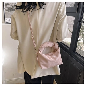 Detail of pink pleated crossbody bag with a knot handle and golden metal hardware
