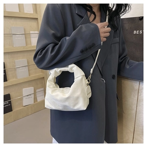 Detail of white pleated cloud bag with metallic fashion tag and detachable strap