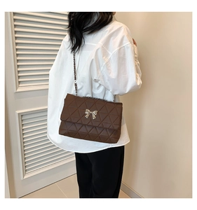 Quilted dark brown crossbody bag with silver bow clasp shown on model for size and fit